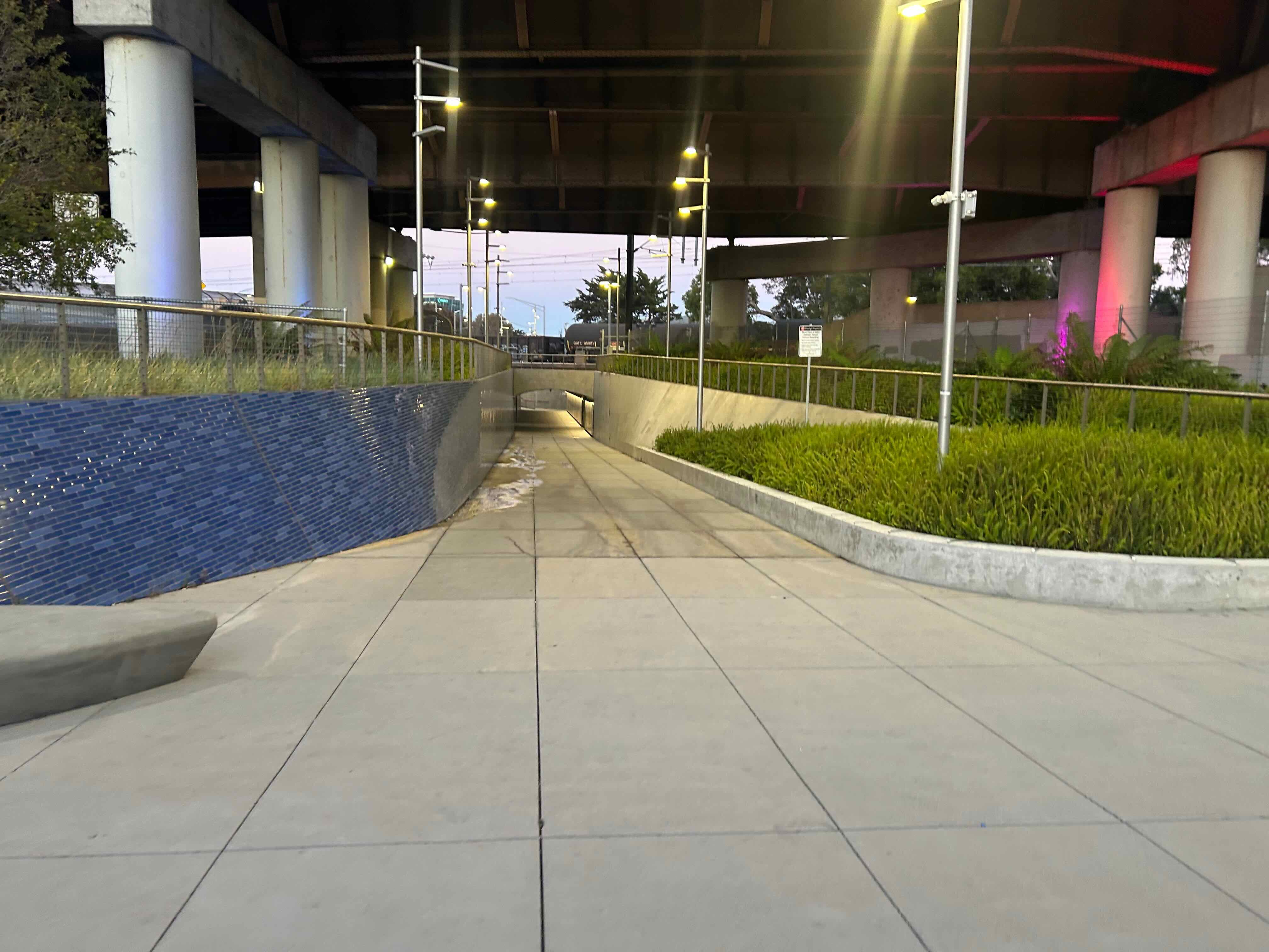 A wide concrete ramp leading into a tunnel under the tracks. 